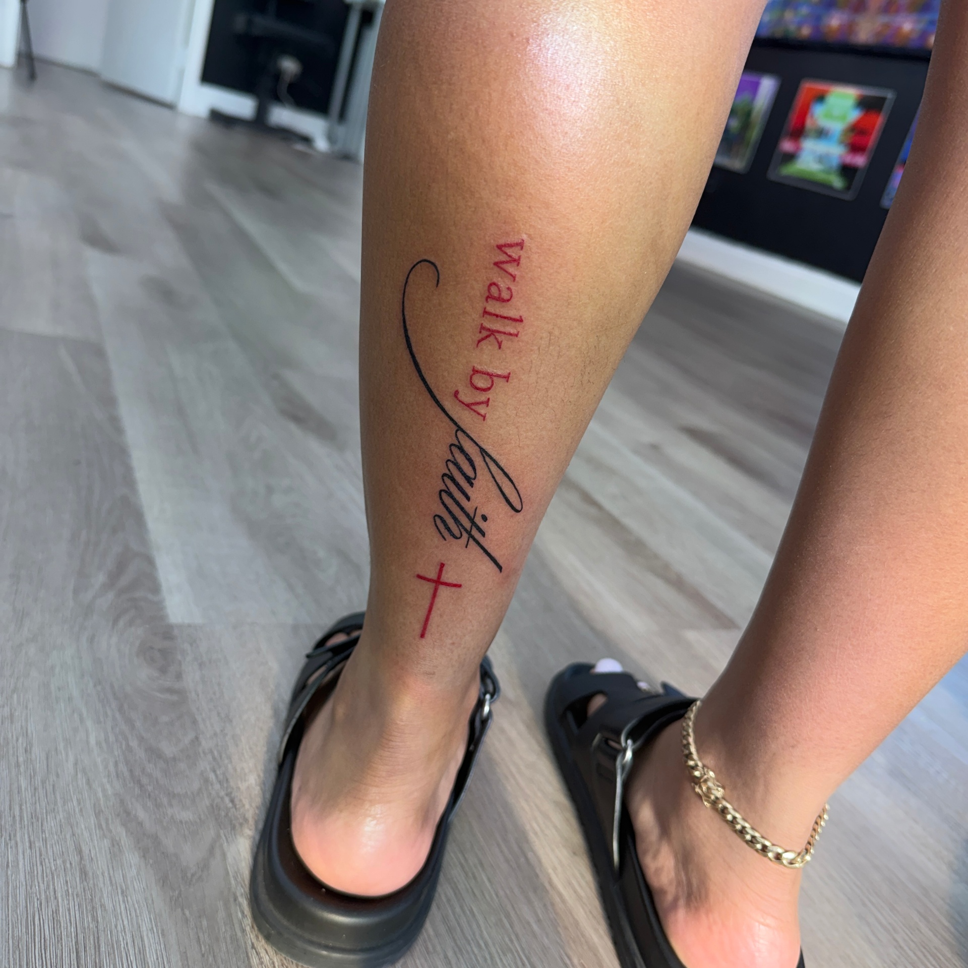 'Walk by faith' script tattoo with red cross on calf