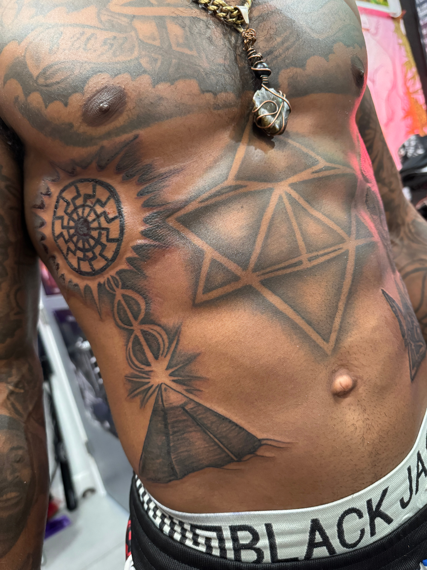 Large-scale black and grey chest and torso tattoo with sacred geometry and pyramid