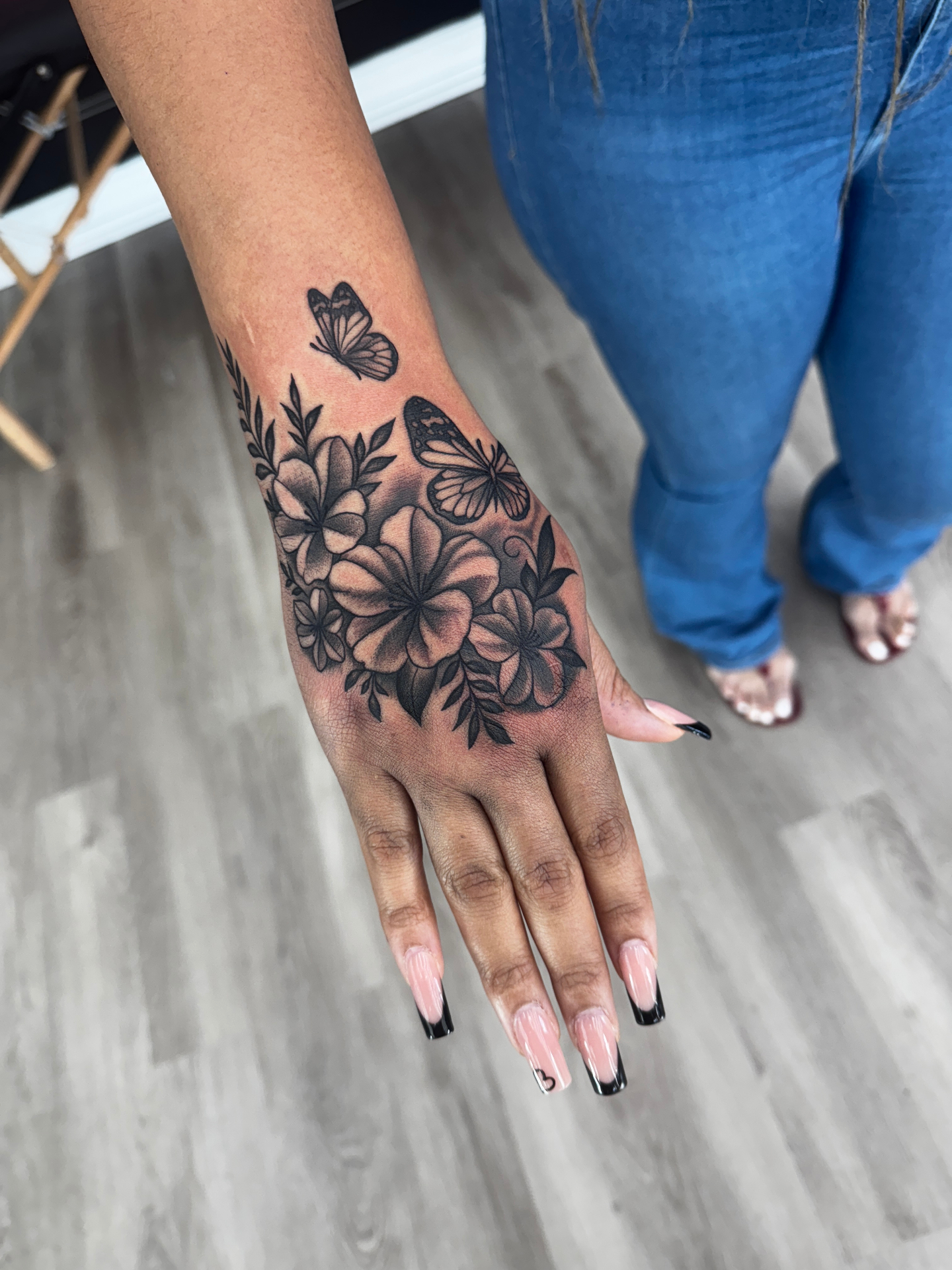 Black and grey floral and butterfly hand tattoo