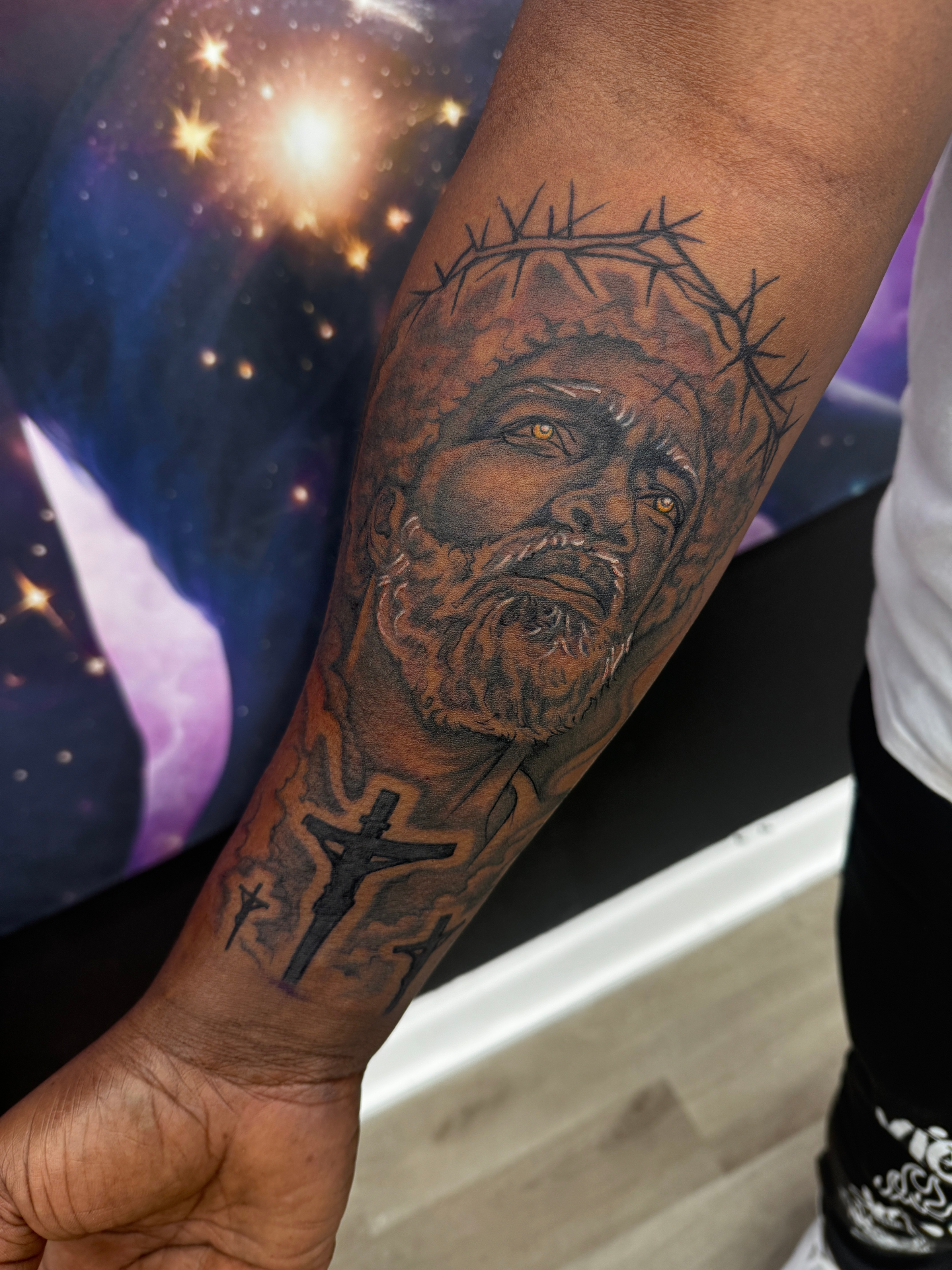 Realistic black and grey Jesus portrait forearm tattoo with crown of thorns