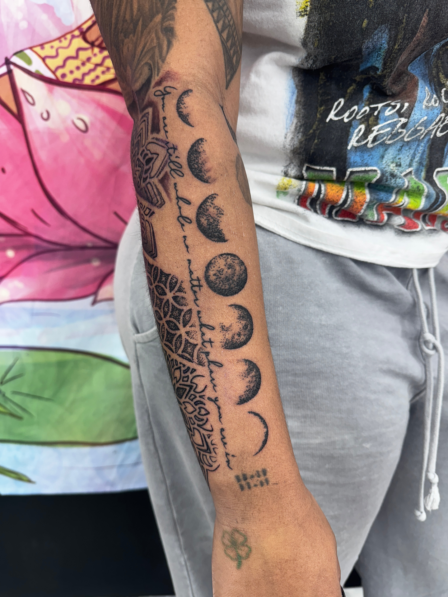Black and grey moon phases and script forearm tattoo