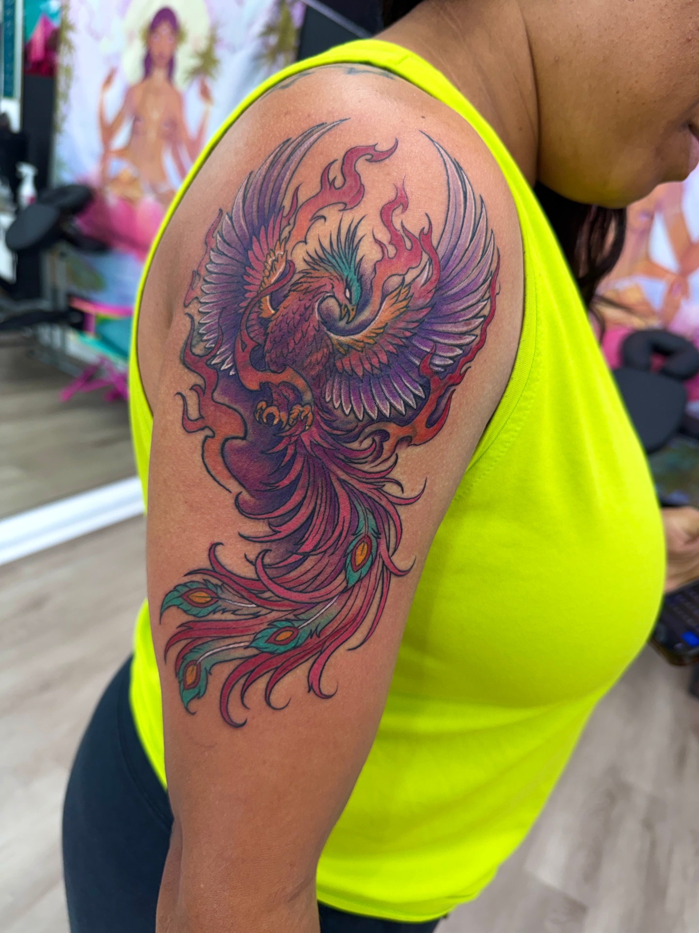 Vibrant color phoenix shoulder tattoo with flames and peacock feathers