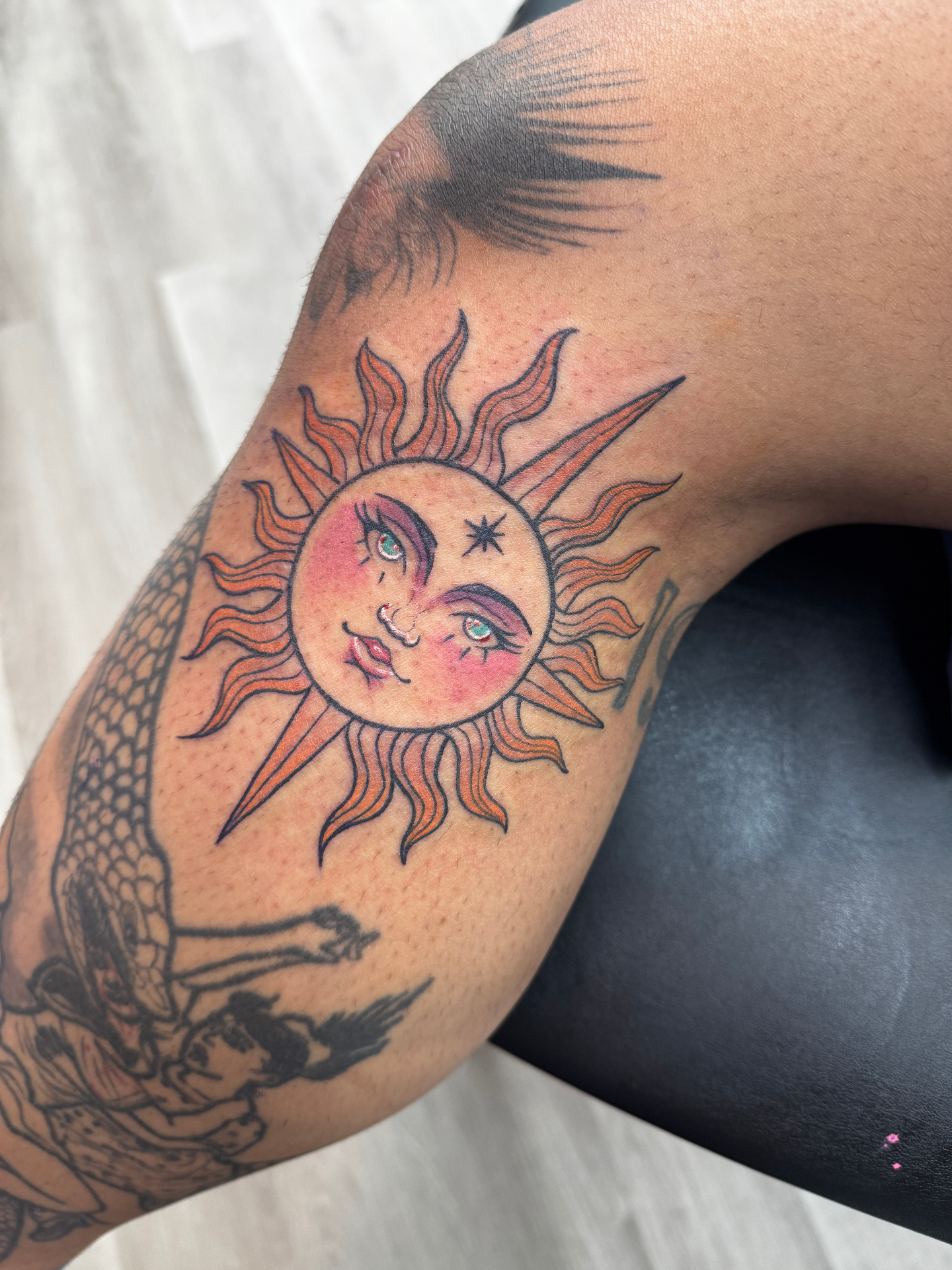 Traditional color sun tattoo with face on knee
