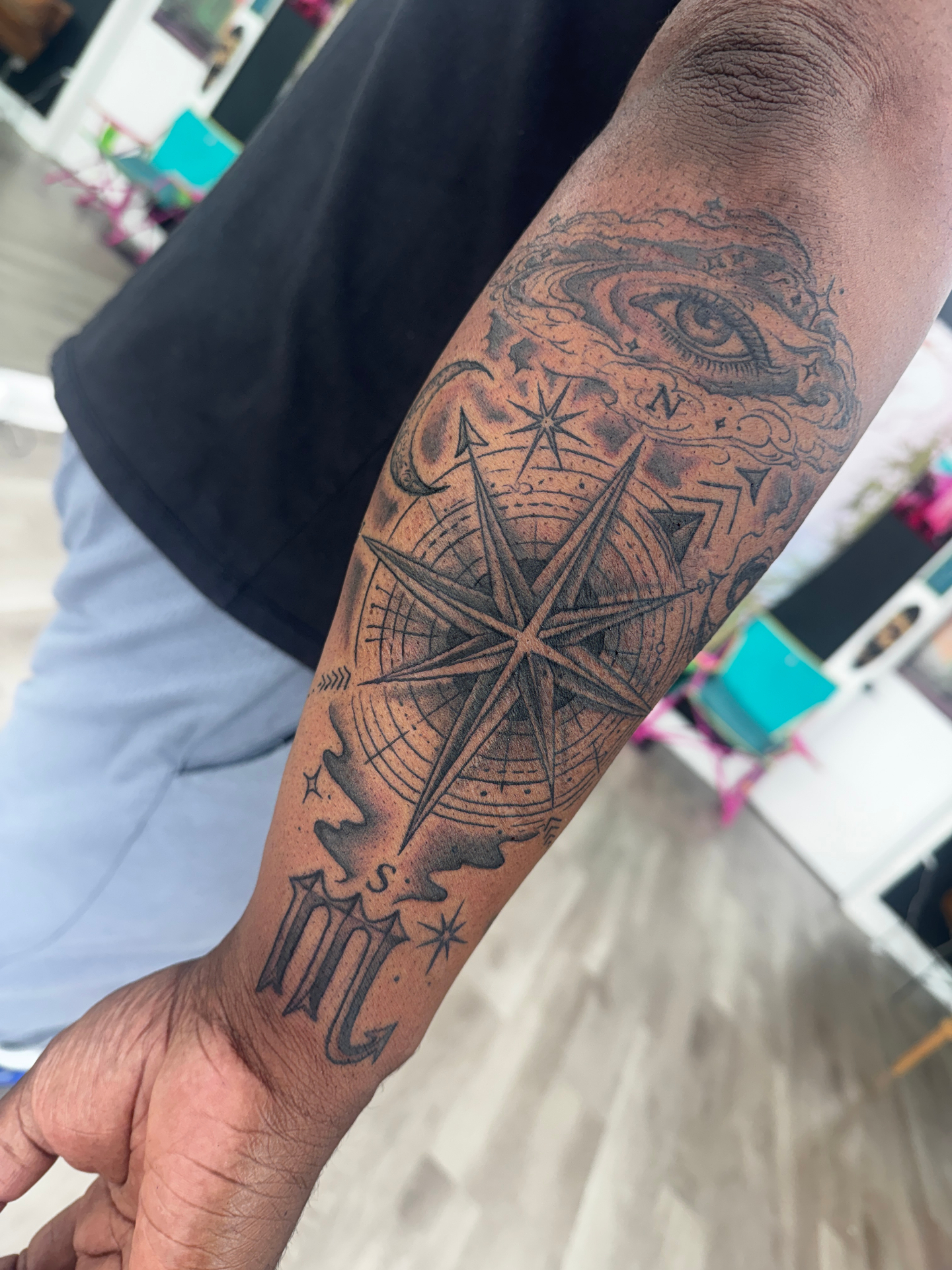 Black and grey compass and eye forearm tattoo